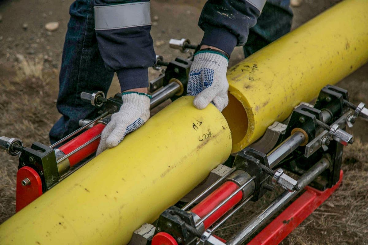 Hands holding a length of pipe during an installation