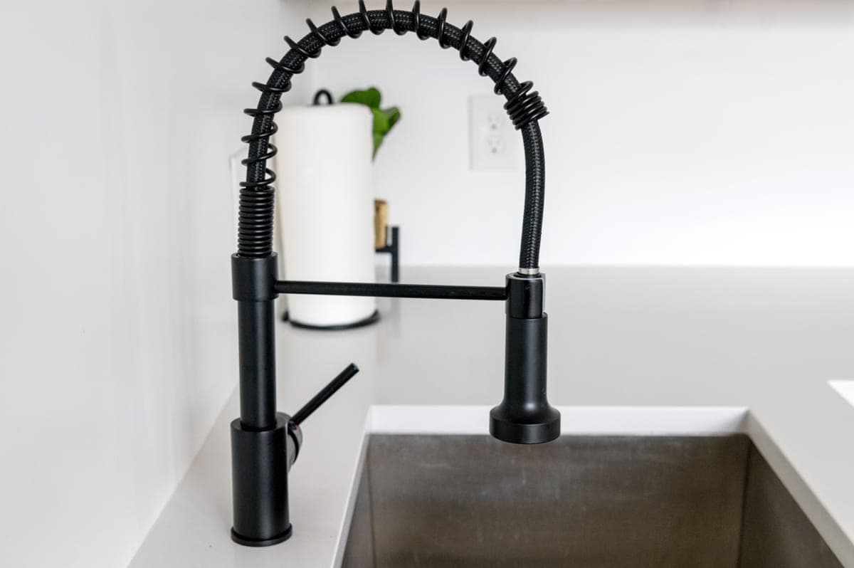 A kitchen sink with a tall black faucet