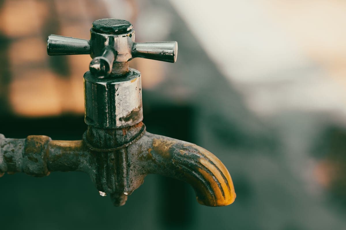 A close view of a faucet spout with heavy mineral scale