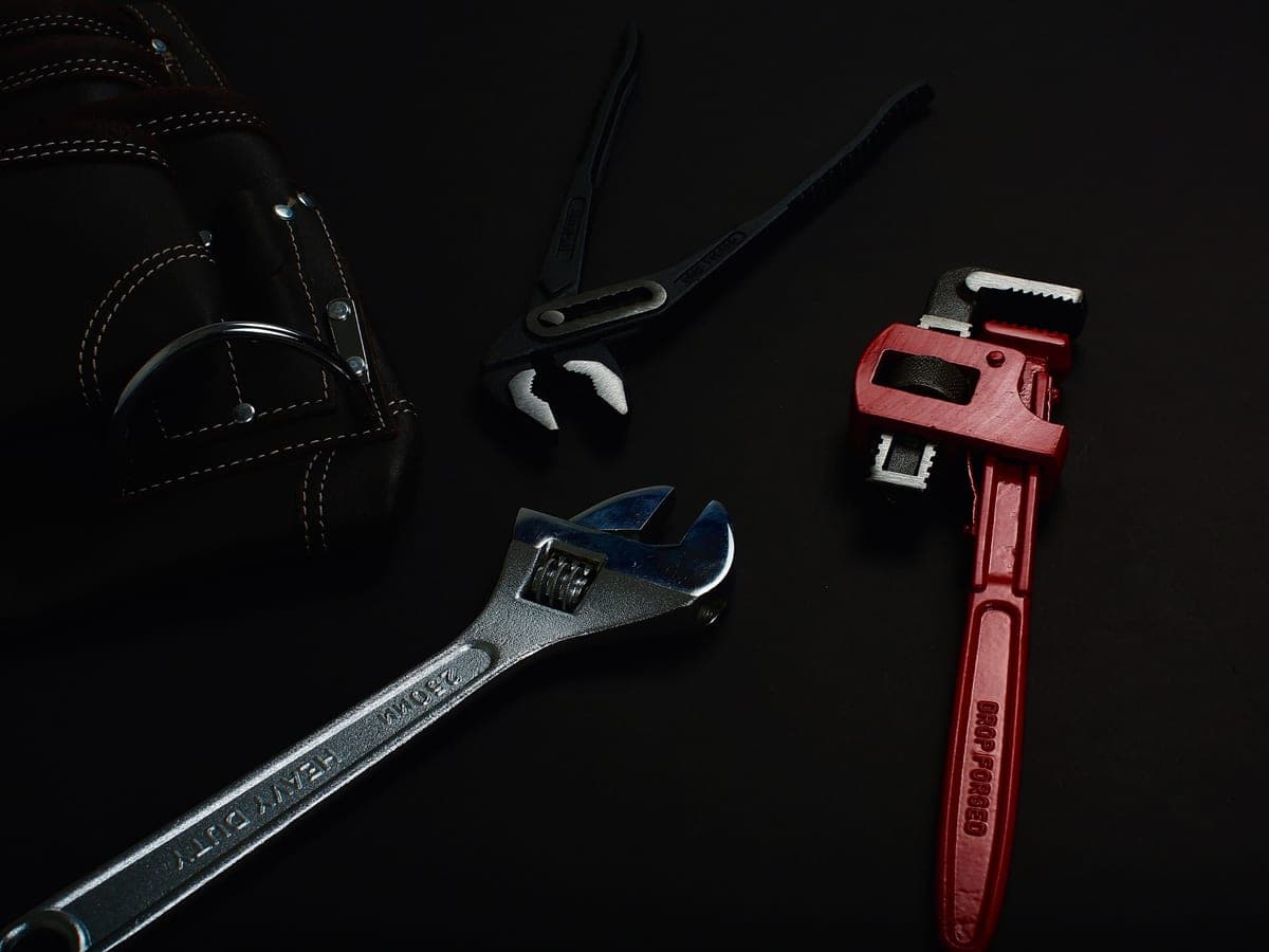 A pipe wrench and hand tools on a work surface